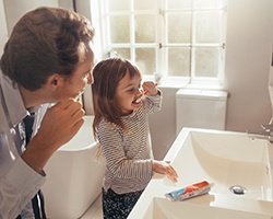 father teaching daughter how to brush teeth 