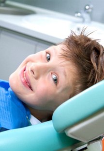 young patient giving thumbs up while sitting in treatment chair  