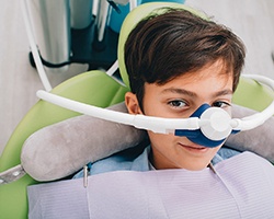 A young boy seated in the dentist’s chair wearing a nasal mask in preparation to receive nitrous oxide