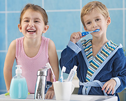 Young girl and boy in pjs brushing teeth