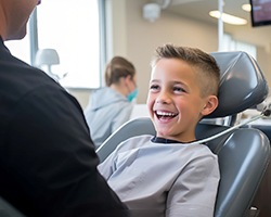 Young child smiling at pediatric dentist while sitting in treatment chair