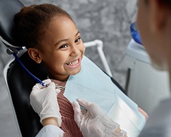 Child smiling at pediatric dentist during dental checkup