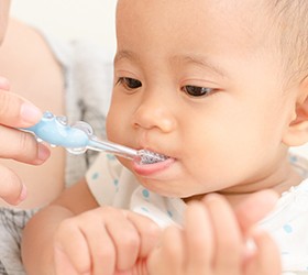 A parent helping to brush their baby’s teeth using a small toothbrush