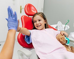 A little girl gives her sedation dentist in Birmingham a high-five after completing a dental checkup and cleaning