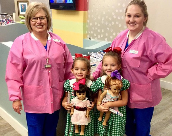 two team members with two young girl patients in matching dresses