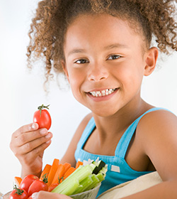 Young girl holding tomato and smiling