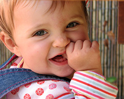 baby girl smiling with thumb in mouth
