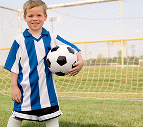 young boy in soccer uniform holding soccer ball