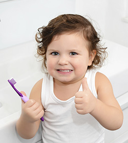 young girl doing thumbs up and holding toothbrush