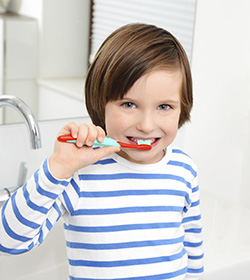 young boy wearing striped shirt brushing teeth