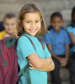 young girl crossing arms smiling with backpack on