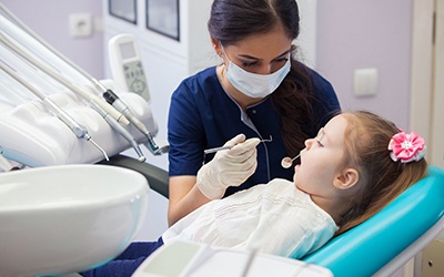 A little girl having her teeth checked by a dental hygienist during a regular appointment