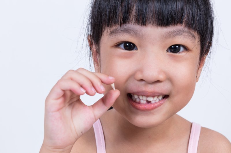 small girl holding a loose tooth
